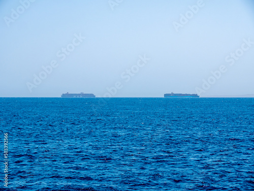 Two large cargo ships carrying containers by sea.