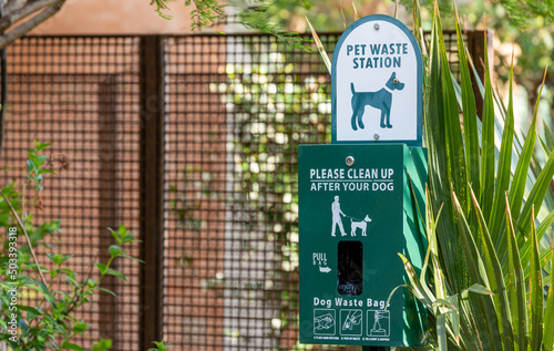 Pet waste station in park with plastic bags and instructions for use. Public dog feces disposal station.