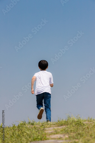 初夏の野原で遊んでいる小学生の男の子の姿 © zheng qiang
