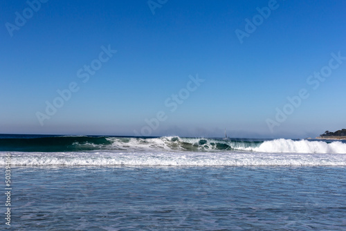A view on ocean with white waves and blue sky