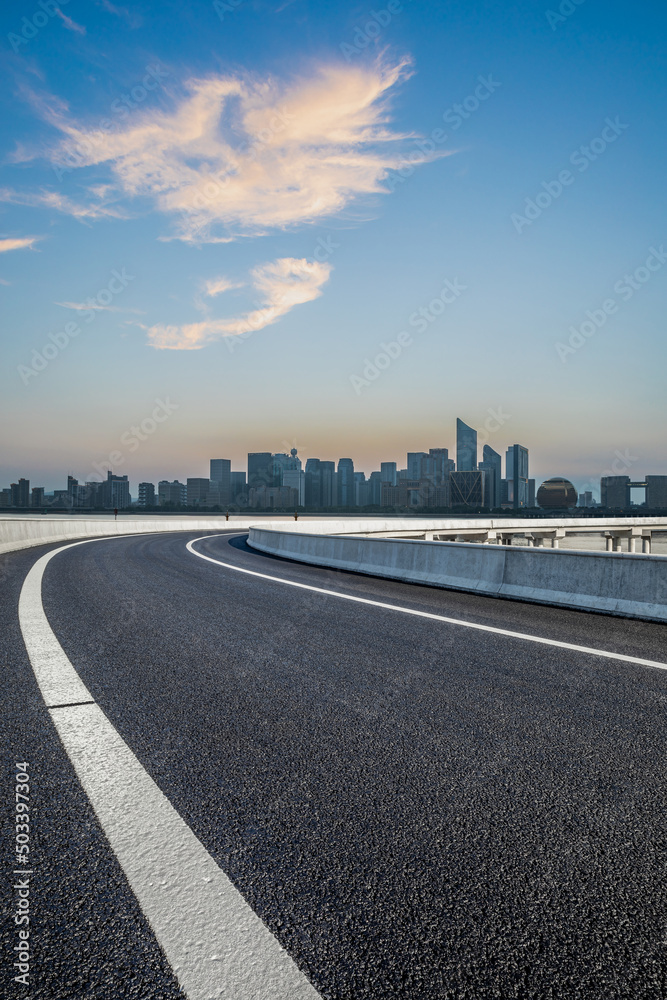 Empty asphalt road and modern city skyline with buildings in Hangzhou at sunset, China.