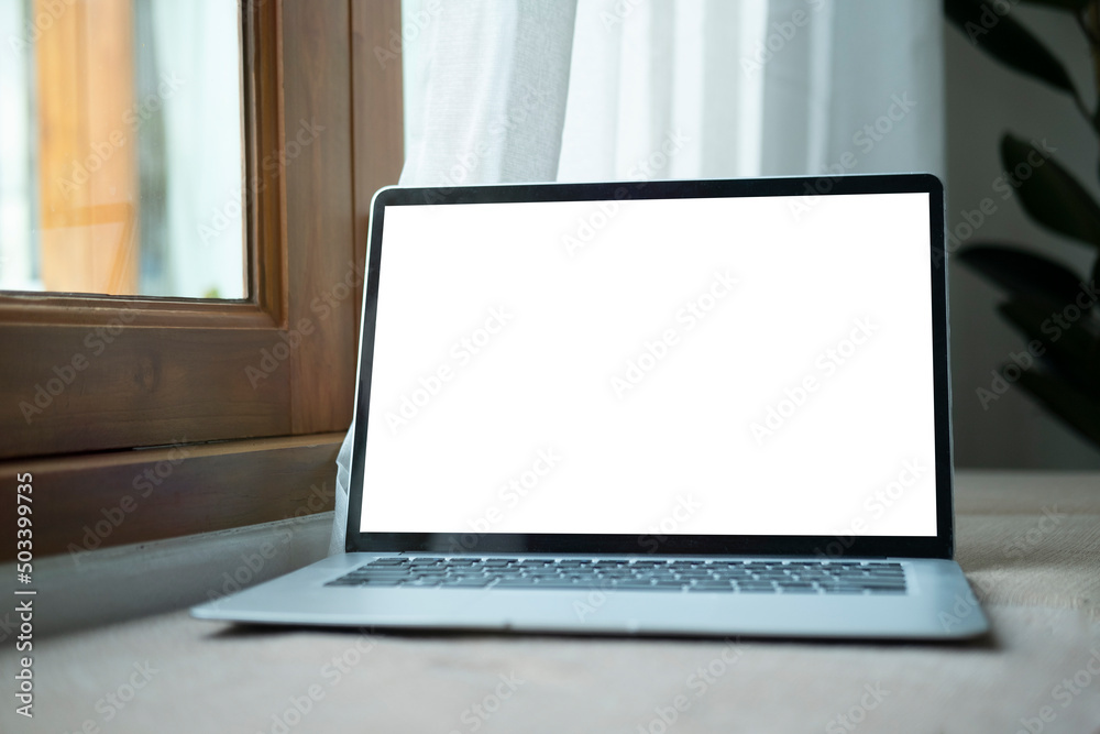 Fototapeta premium Mock up computer laptop with blank screen on wooden table at comfortable workplace.