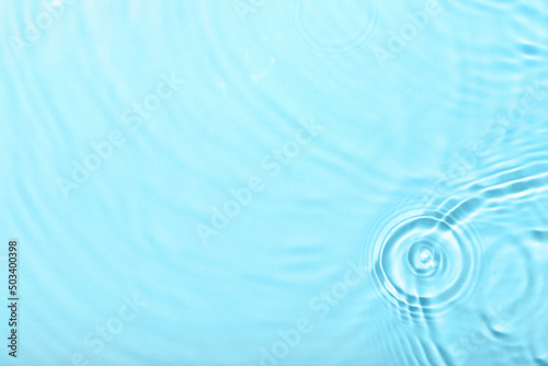 Clean water with splashes on color background