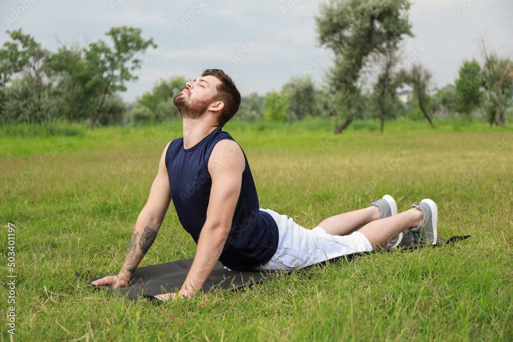 Sporty young man exercising on mat in park Sporty young man exercising on mat in park