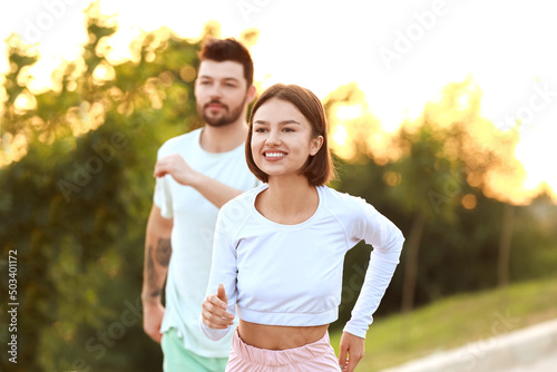 Fototapeta Naklejka Na Ścianę i Meble -  Sporty young woman running with her boyfriend outdoors