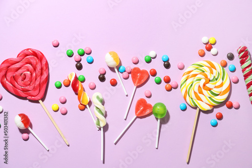 Different lollipops and candies on lilac background, closeup