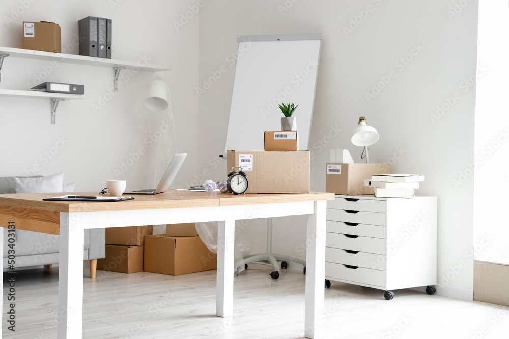 Cardboard boxes with belongings and furniture in interior of office on moving day Cardboard boxes with belongings and furniture in interior of office on moving day