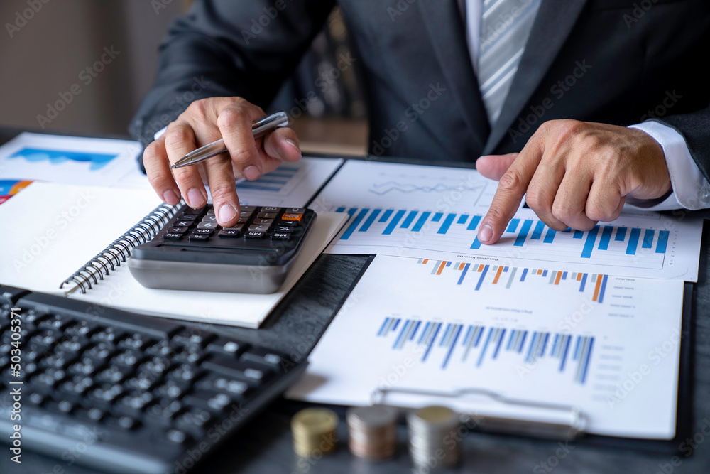 Accountant man hand press on a calculator for make financial report or company's profit monthly at desk, bookkeeper job and work from home concept Accountant man hand press on a calculator for make financial report or company's profit monthly at desk, bookkeeper job and work from home concept