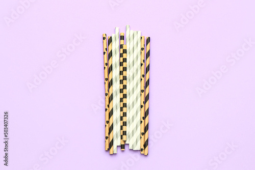 Stylish straws for drinks on purple background