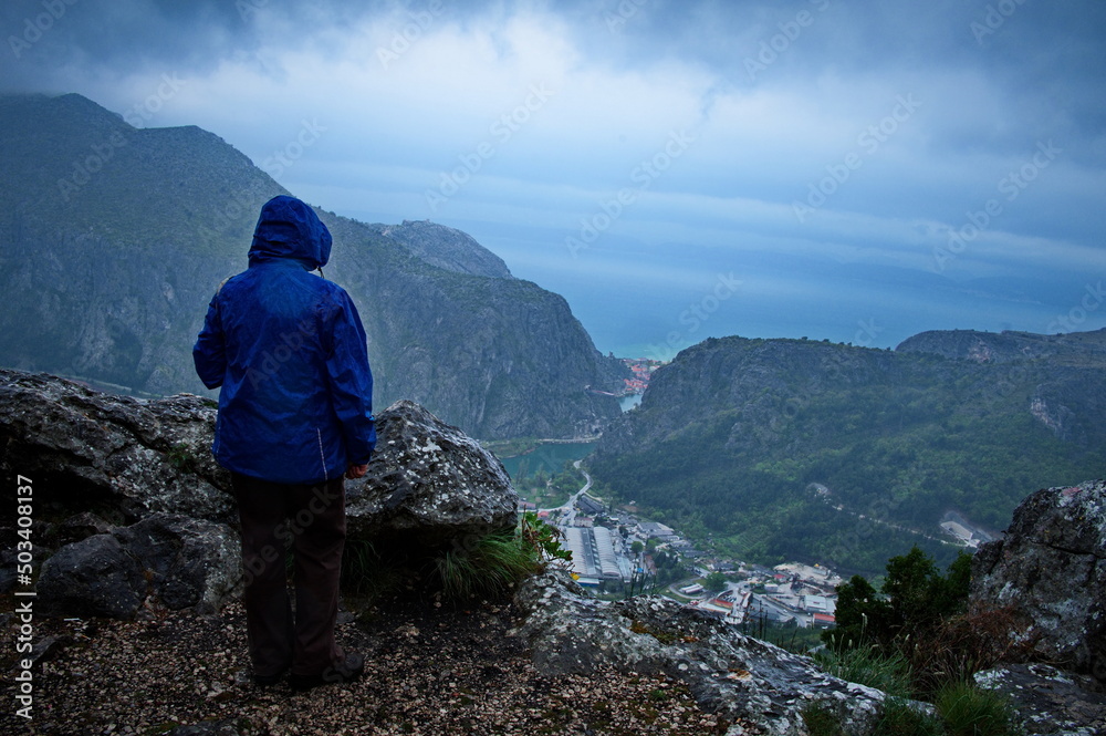 Rear view of woman standing on the top of the hill on a rainy day