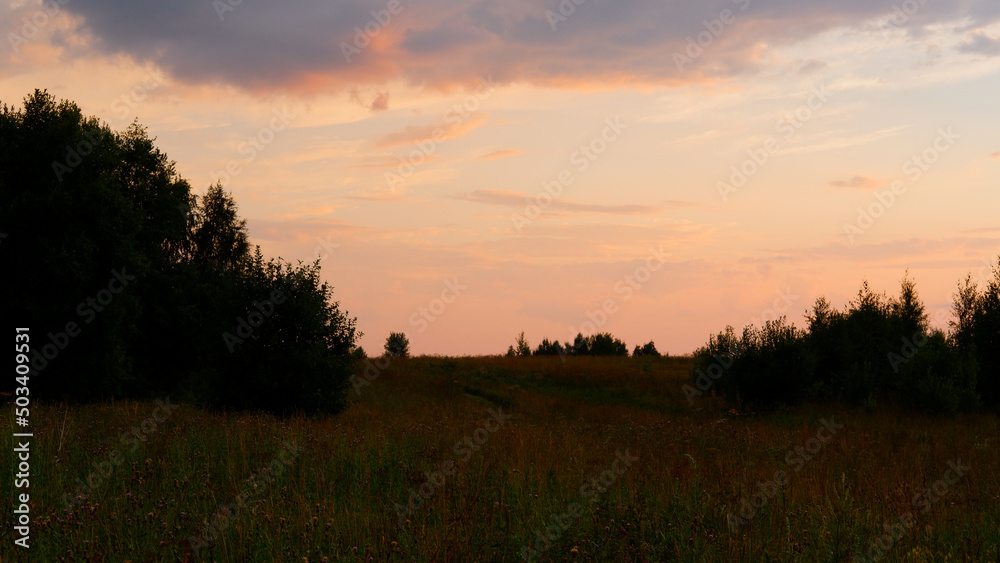 Rural landscape with field at sunset and village in the background. Vologda region Rural landscape with field at sunset and village in the background. Vologda region