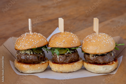 mini burger sliders on a wooden board up close low light with grain and out of focus