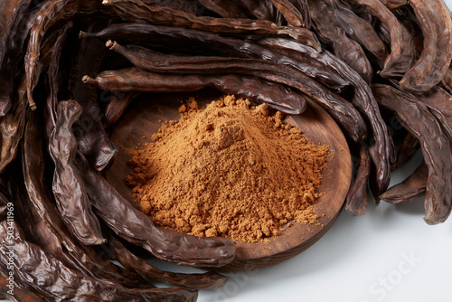 Obraz na plátně In the foreground, a wooden bowl with carob flour