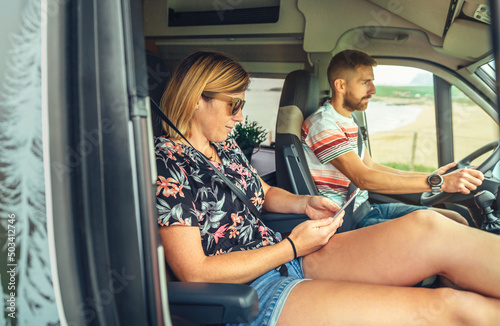 Couple traveling in camper van. Man driving and woman looking at mobile © David Pereiras