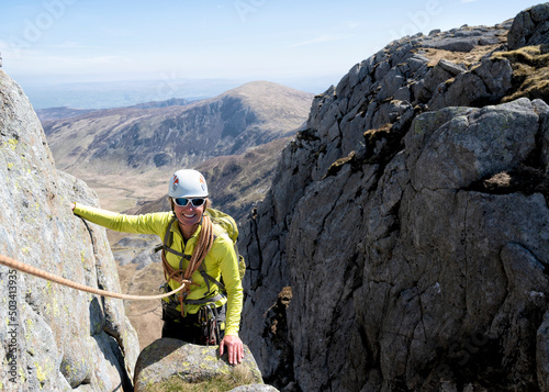 Smiling senior woman wearing helmet on rocky mountain peak photo