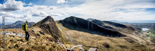 Active woman with backpack standing on mountain ridge
