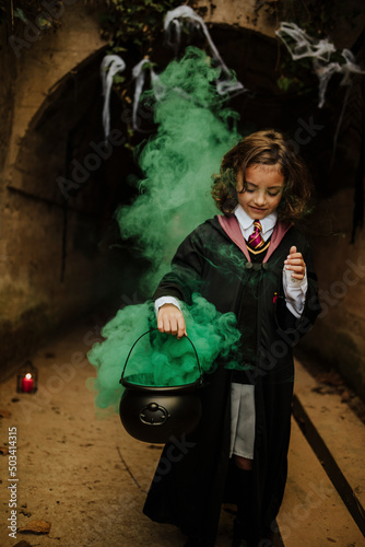Smiling girl wearing costume holding cauldron with witches brew photo