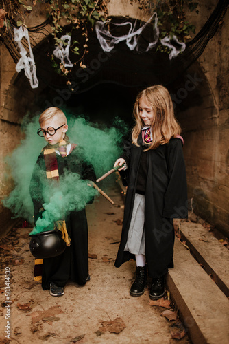 Smiling girl with brother holding magic cauldron standing in front of tunnel