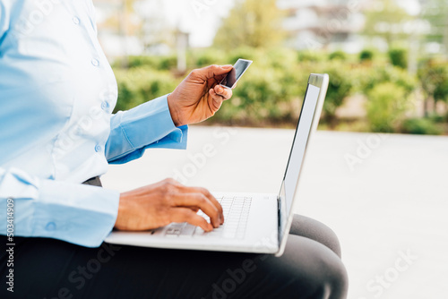 Businesswoman holding credit card doing online shopping through laptop