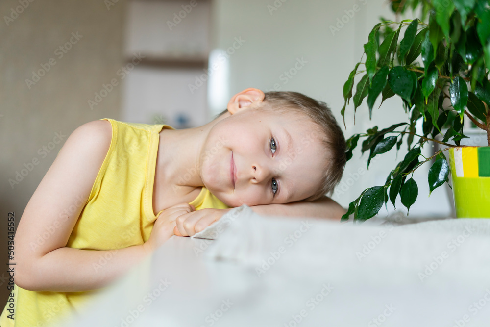 Smiling boy leaning head on table at home