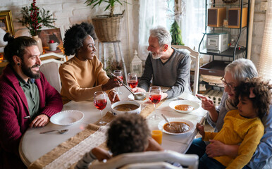 Happy multiethnic multigeneration family having fun together around kitchen table.