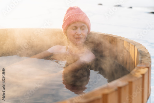 Relaxed shirtless woman enjoying hot water bath in winter