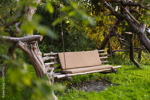 Porch swing with soft cushions in spring park at countryside
