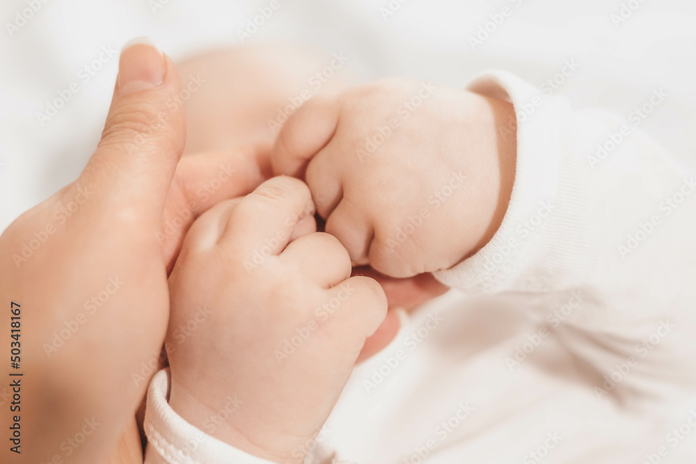 baby's hands holding mother's hand. The emotional bond between mother and child. Development of motor skills of hands baby's hands holding mother's hand. The emotional bond between mother and child. Development of motor skills of hands