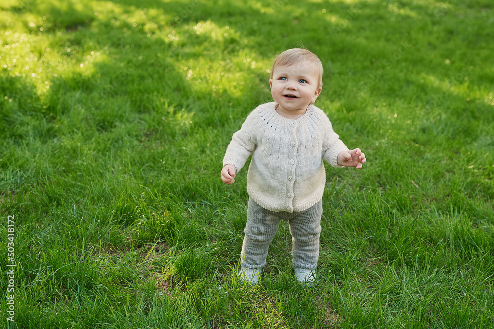 Smiling baby boy on grass in park. Children Protection Day. World Children's Day Smiling baby boy on grass in park. Children Protection Day. World Children's Day