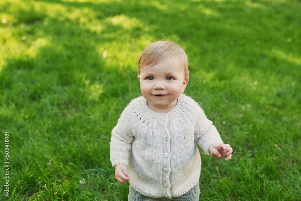 Smiling baby boy on grass in park. Children Protection Day. World Children's Day Smiling baby boy on grass in park. Children Protection Day. World Children's Day