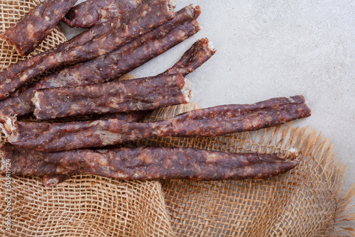 South African Dry Wors, a dried and cured sausage snack on grey, with copy space