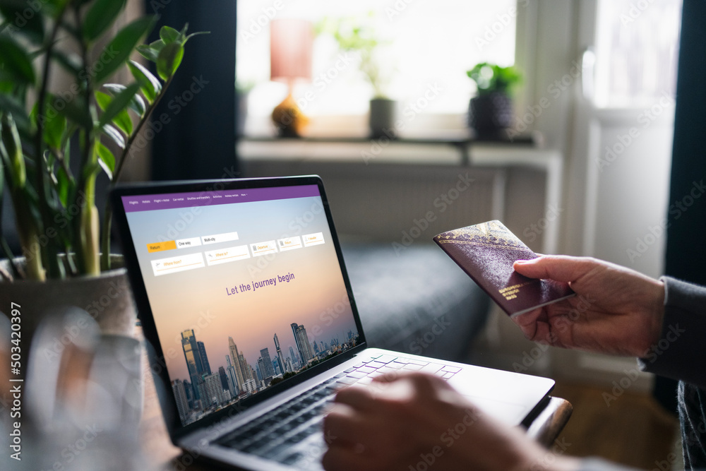 Man searching for flights on laptop and holding passport Man searching for flights on laptop and holding passport
