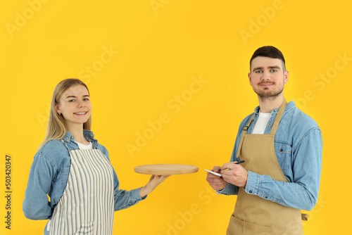 Concept of occupation, young waiters on yellow background