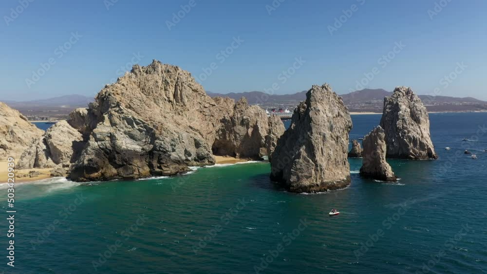 Drone shot of Playa del Amor and El Arco natural sea cliffs with boats in the ocean in Cabo San Lucas Mexico, wide and rotating Drone shot of Playa del Amor and El Arco natural sea cliffs with boats in the ocean in Cabo San Lucas Mexico, wide and rotating