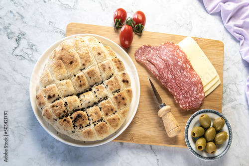 table with bread and cold cuts, salami, cheese, tomatoes, olives, ideal for a snack photo