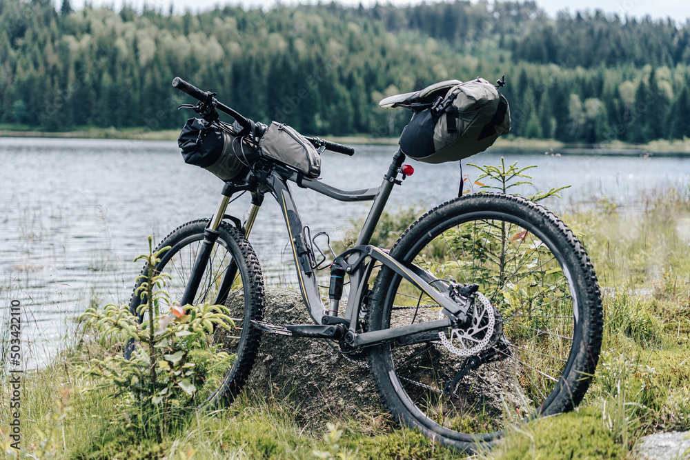 Bikepacking equipment on a mountain bike. Mountain bike with packed travel gear, bike packing gear ready to ride and camp outdoors.