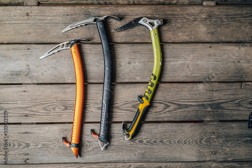 Detail photo of different ice climbing tools. Ice climbing gear, ice axe on a wooden background. Alpinist or mountaineer climbing equipment. photo