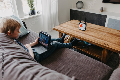 Boy spending time with laptop according to clock photo