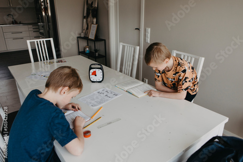 Schoolboys doing homework according to clock photo