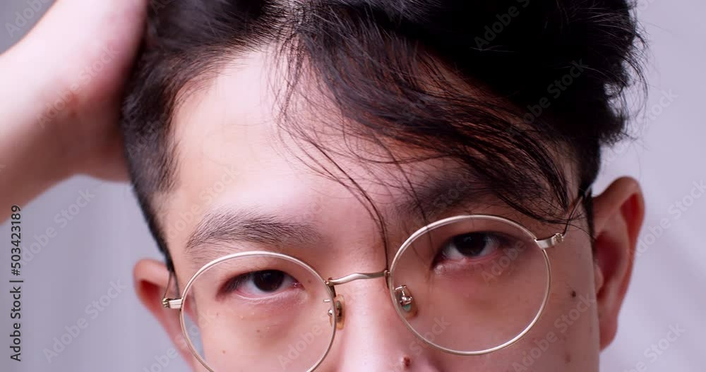 Close up Asian man with glasses and healthy good hair looking to the camera and spoiling himself by tidying his hair. Slow motion. Close up Asian man with glasses and healthy good hair looking to the camera and spoiling himself by tidying his hair. Slow motion.