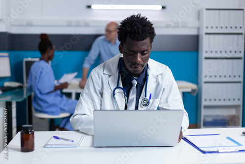 Practitioner expert using laptop in healthcare facility cabinet. Clinic specialist uploading critical patient disease records and prescribed medications to clinic database.