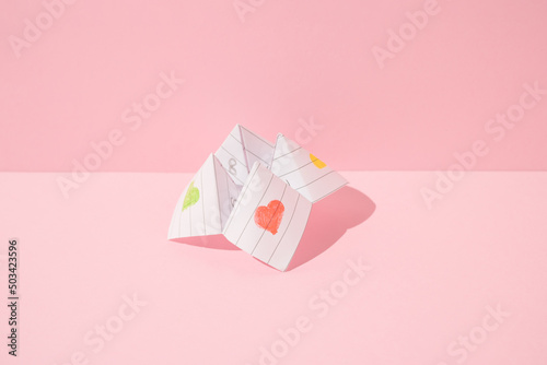 Paper origami fortune teller game on pink background. Minimal concept.