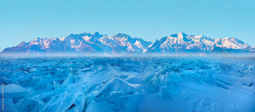 Beautiful winter landscape of frozen Lake Baikal at sunrise - Snowy ice hummocks with transparent blue piles of ice - Baikal Lake, Siberia 