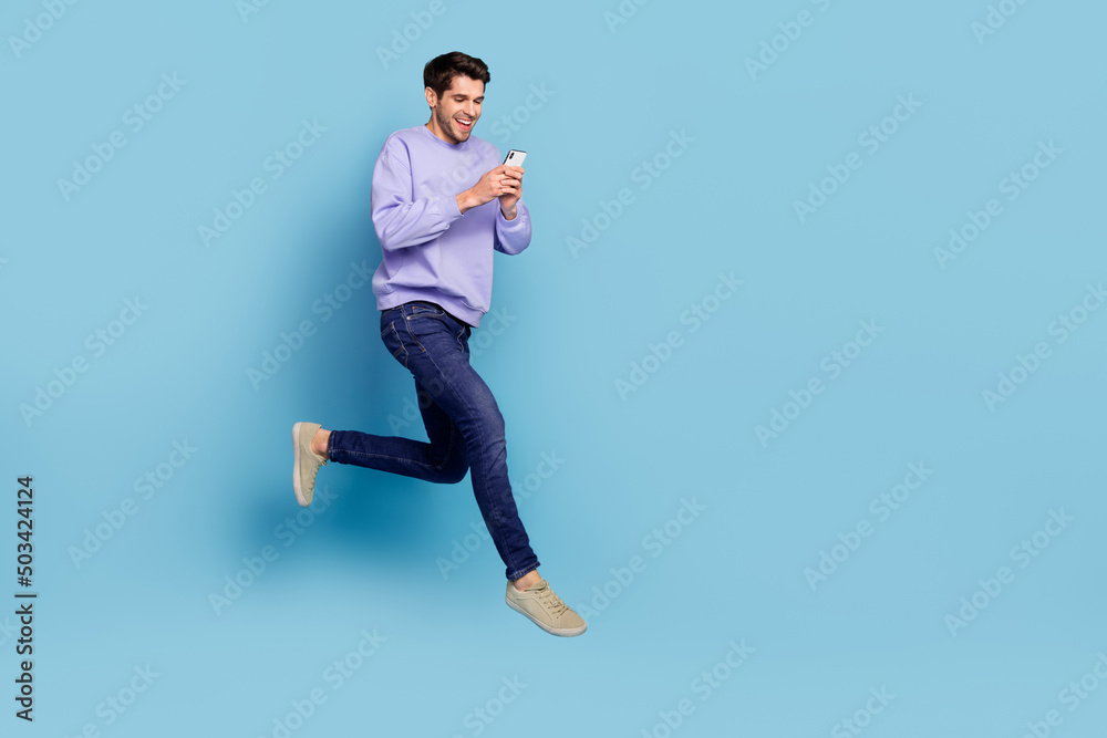 Photo of positive guy jump high use smart device hurry network discounts isolated blue pastel color background