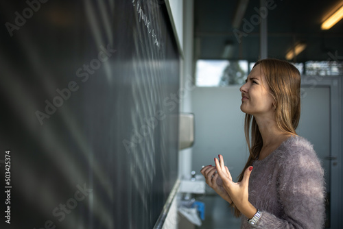 Pretty, young female student in front of a blackboard during math class