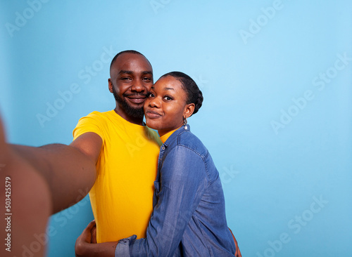 POV of cheerful people holding camera and taking pictures together, expressing love and affection. Man and woman smiling and taking selfies, having fun in relationship. Couple embracing © DC Studio