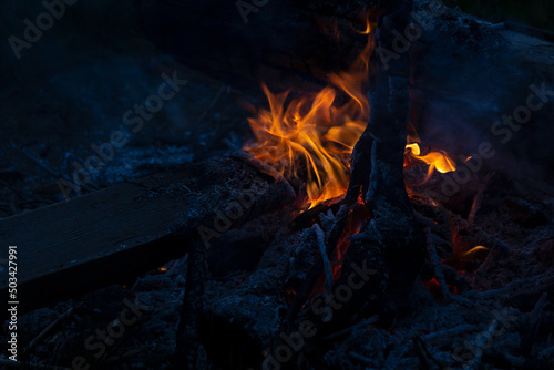 Bright orange bonfire on night camp on dark blue indigo color beach, contrast. Night bonfire on camping.