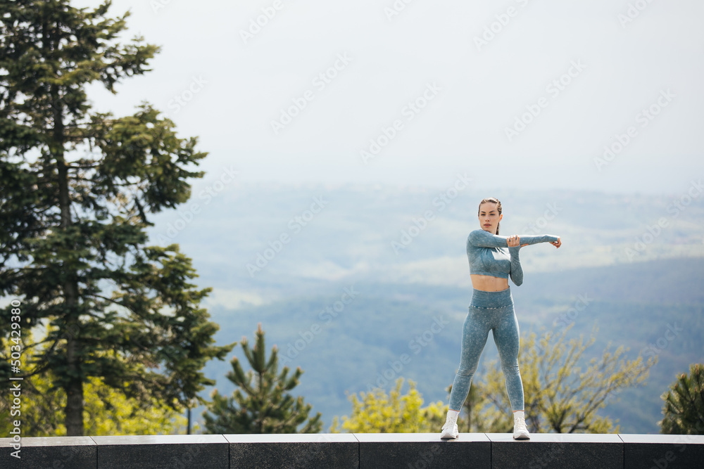 Portrait of beautiful fit woman exercising in the park. Caucasian female fitness model working out in the morning.