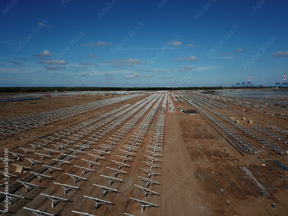 Aerial view of solar power plant under construction on a dirt field. Assembling of electric panels for producing clean ecologic energy. Alternative power concept for sutainable development.