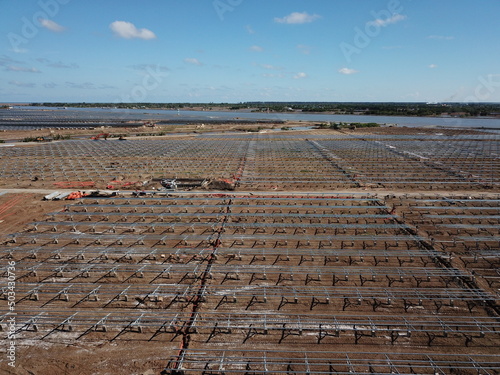 Aerial view of solar power plant under construction on a dirt field. Assembling of electric panels for producing clean ecologic energy. Alternative power concept for sutainable development.